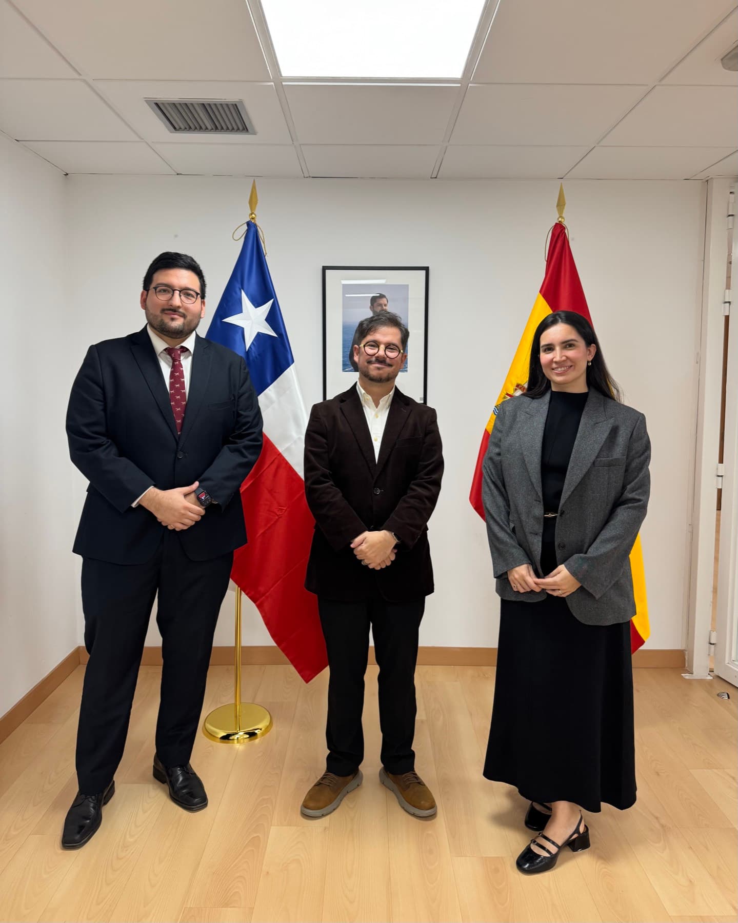 Melanie Moraga y Sebastián León frente a las banderas de Chile y España en la Embajada de Chile en Madrid
